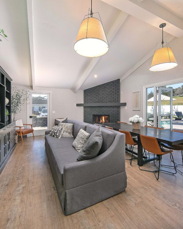 A modern living room with a sectional sofa, black shelving, and a dining area. French doors open to a pool area with lounge chairs outside.