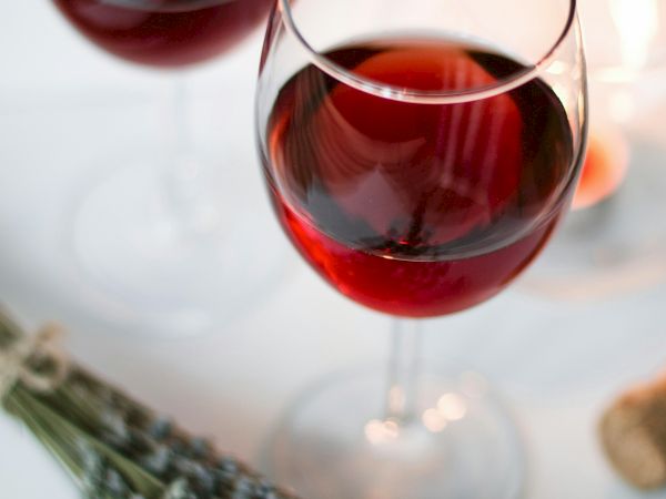 Two glasses of red wine on a table with a lavender bouquet, soft candlelight, and a gentle, romantic ambiance.