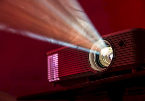 A projector emits a bright beam of light in a dark room, casting a vibrant glow across its surroundings.
